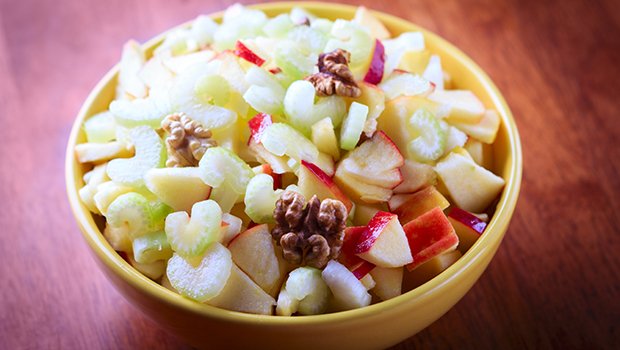 Small yellow bowl containing celery, apples, and walnuts
