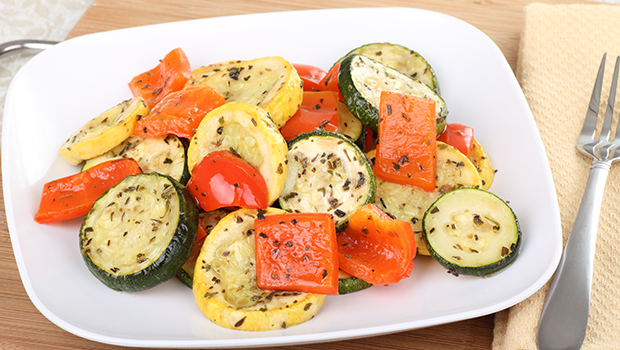 Zucchini rounds with squash and red pepper all on a white square plate